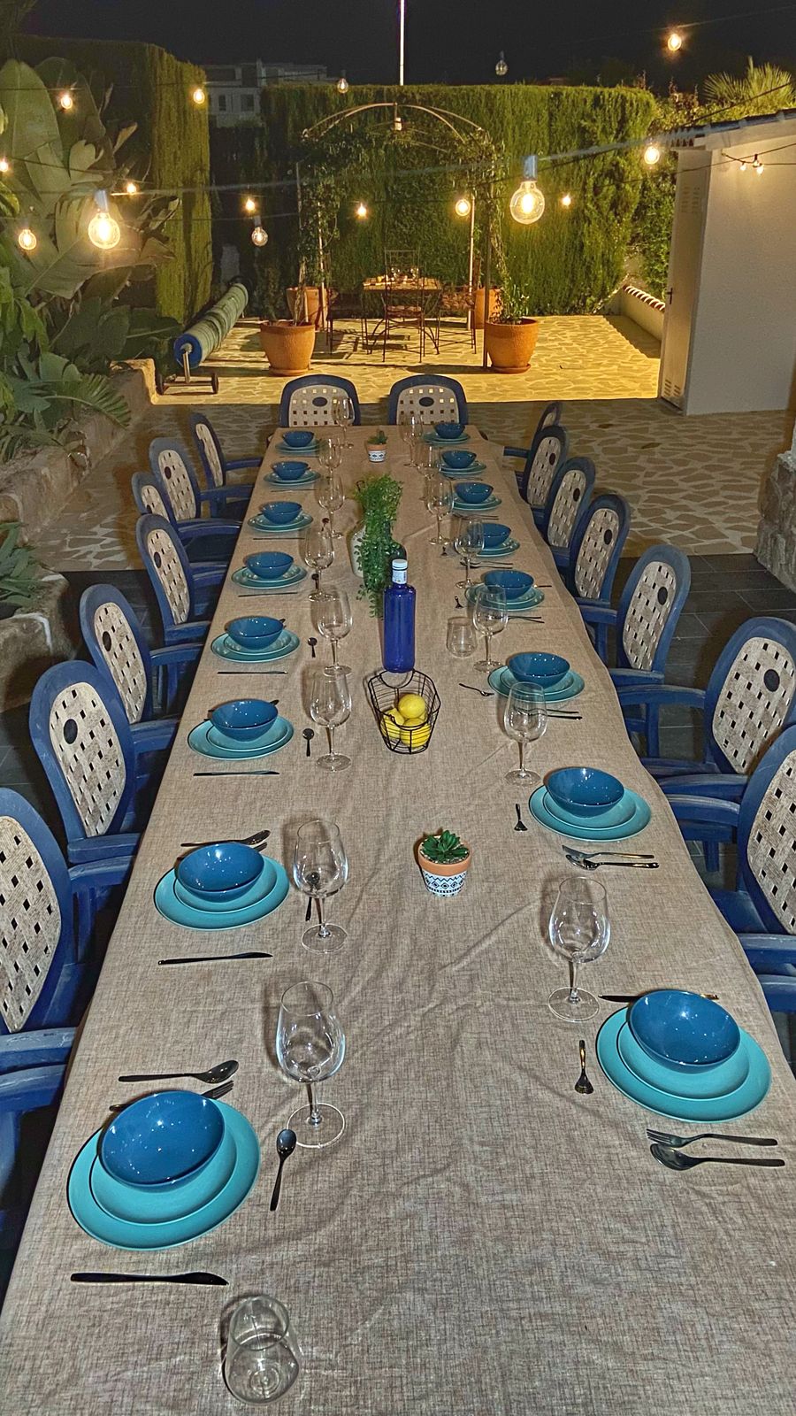 The long table laid with blue crockery at nightfall