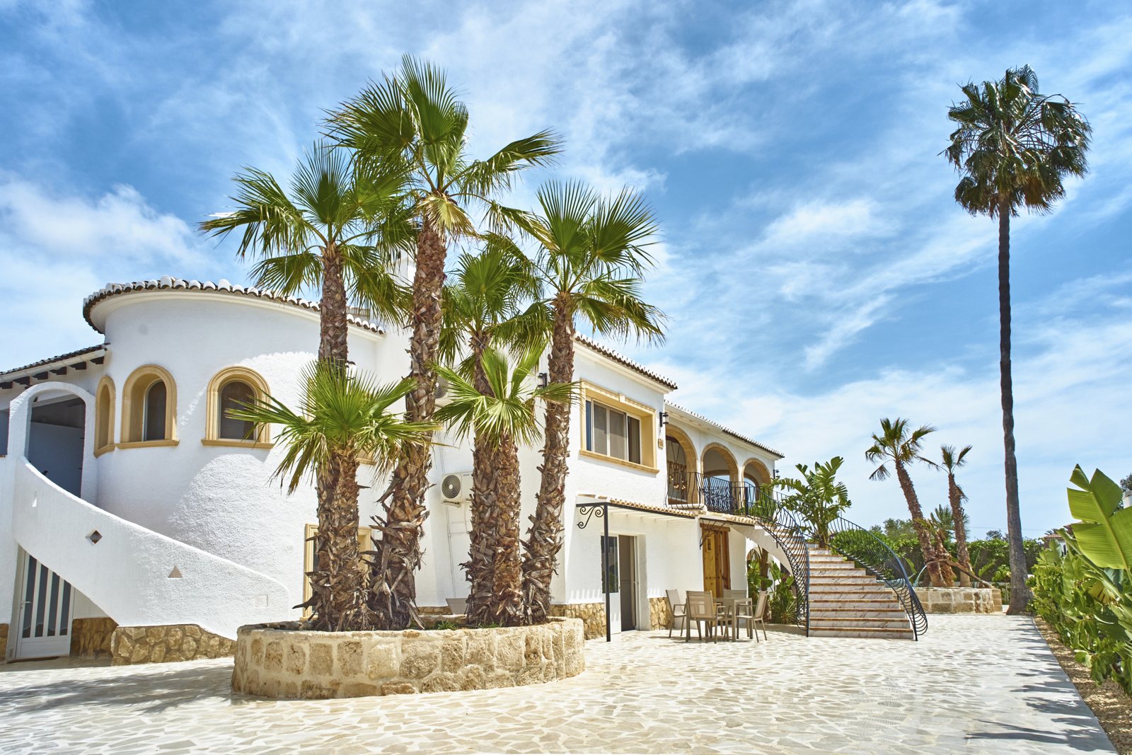 White villa facade with tall palms against a blue sky