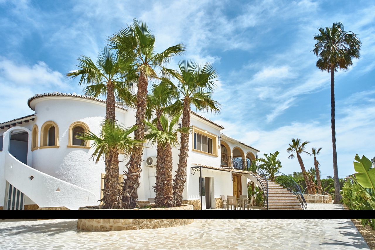 The villa's round tower and palms under a clouded sky