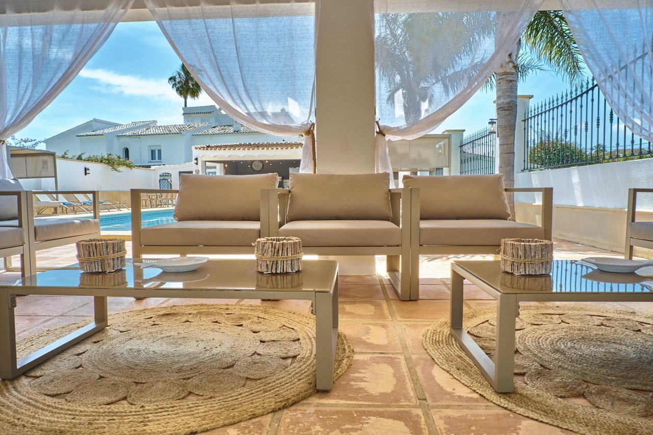 Covered lounge with white curtains looking onto the pool
