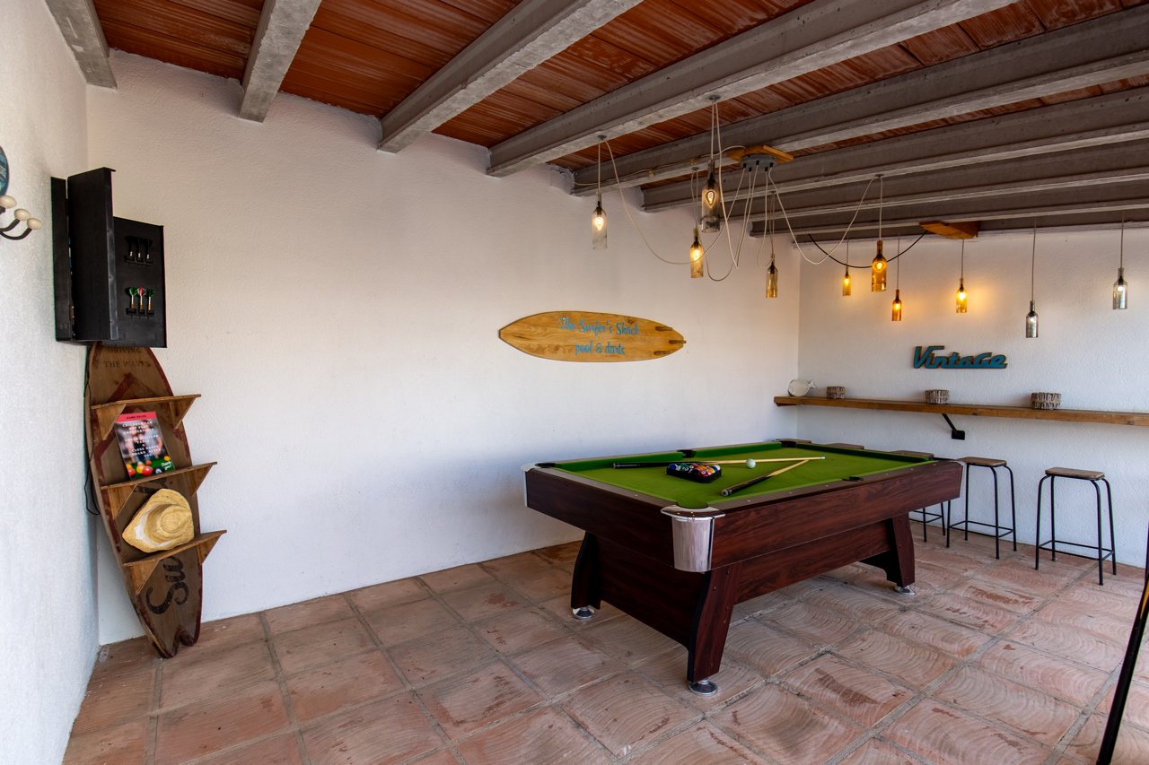 Spielzimmer mit Billardtisch und Surfbrettern unter Balkendecke