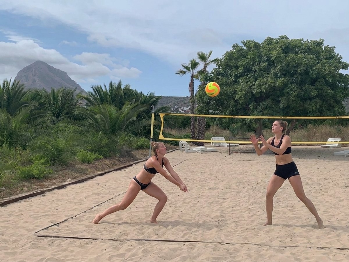Zwei Spielerinnen im Ballwechsel auf dem Beachvolleyballfeld, dahinter der Montgó