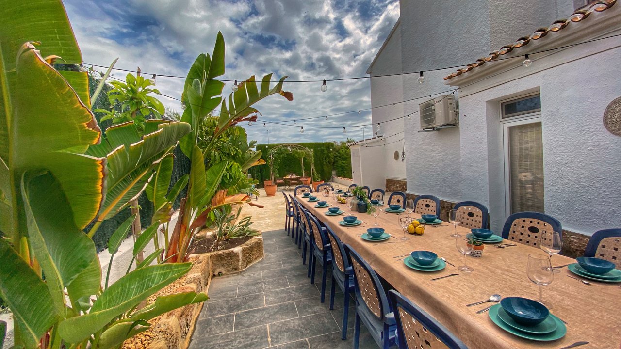 Long table laid with blue crockery between banana plants