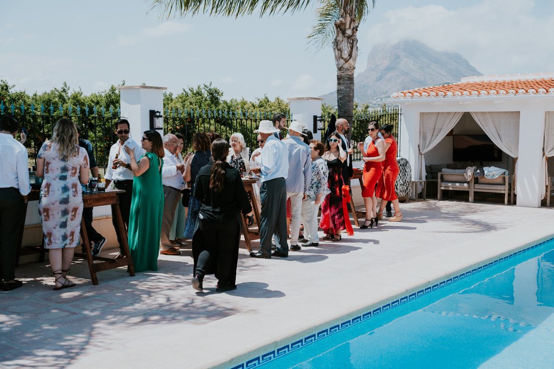Wedding guests with drinks beside the pool, Montgó behind