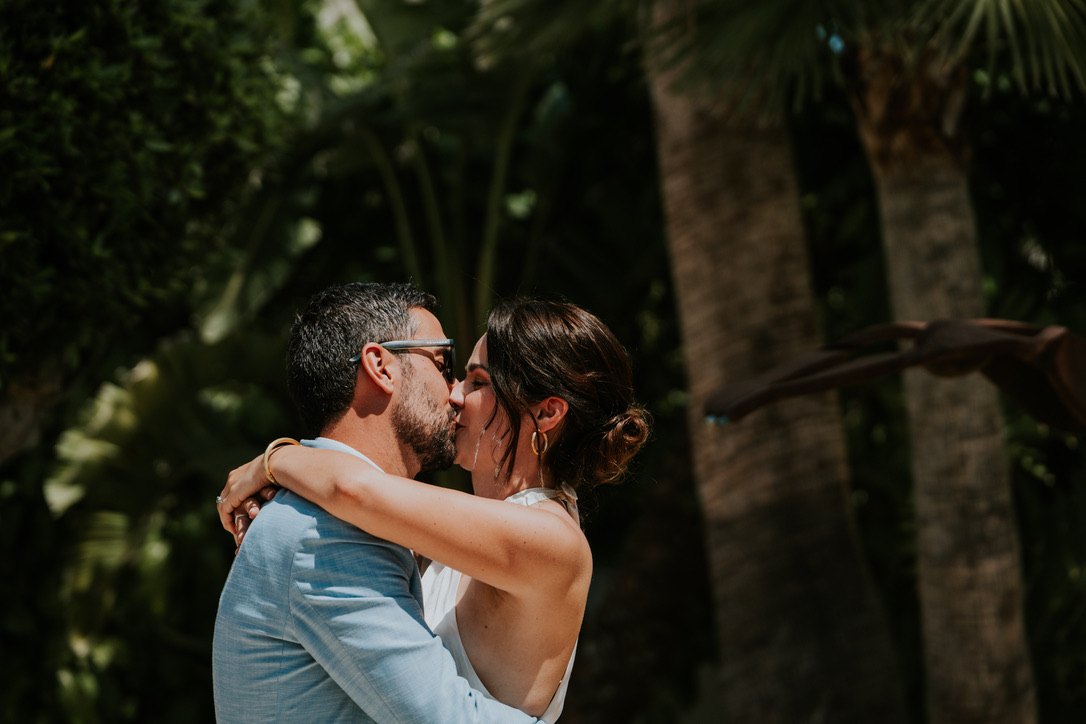 The couple kissing under the palm trees