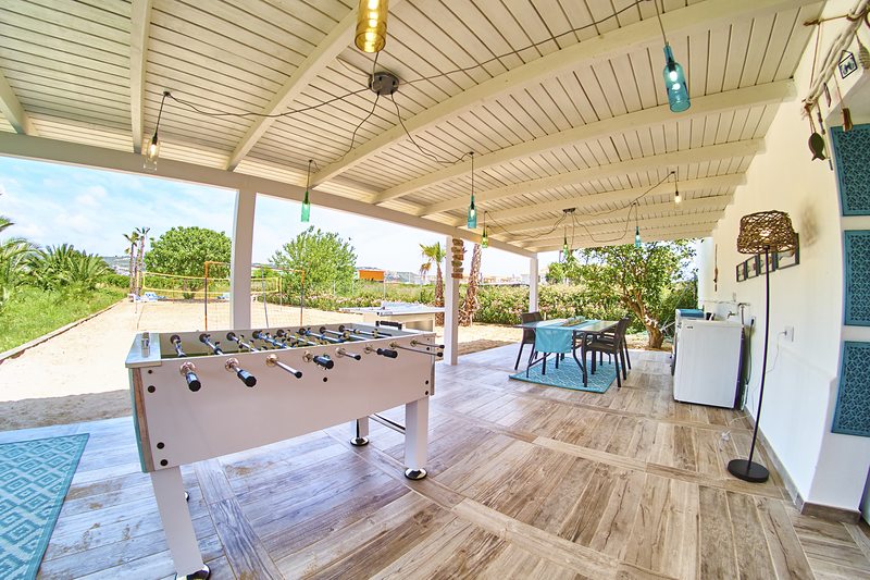 Terraza cubierta con futbolín y vistas a la pista de arena — espacio de juego para toda la familia durante las fiestas en Jávea
