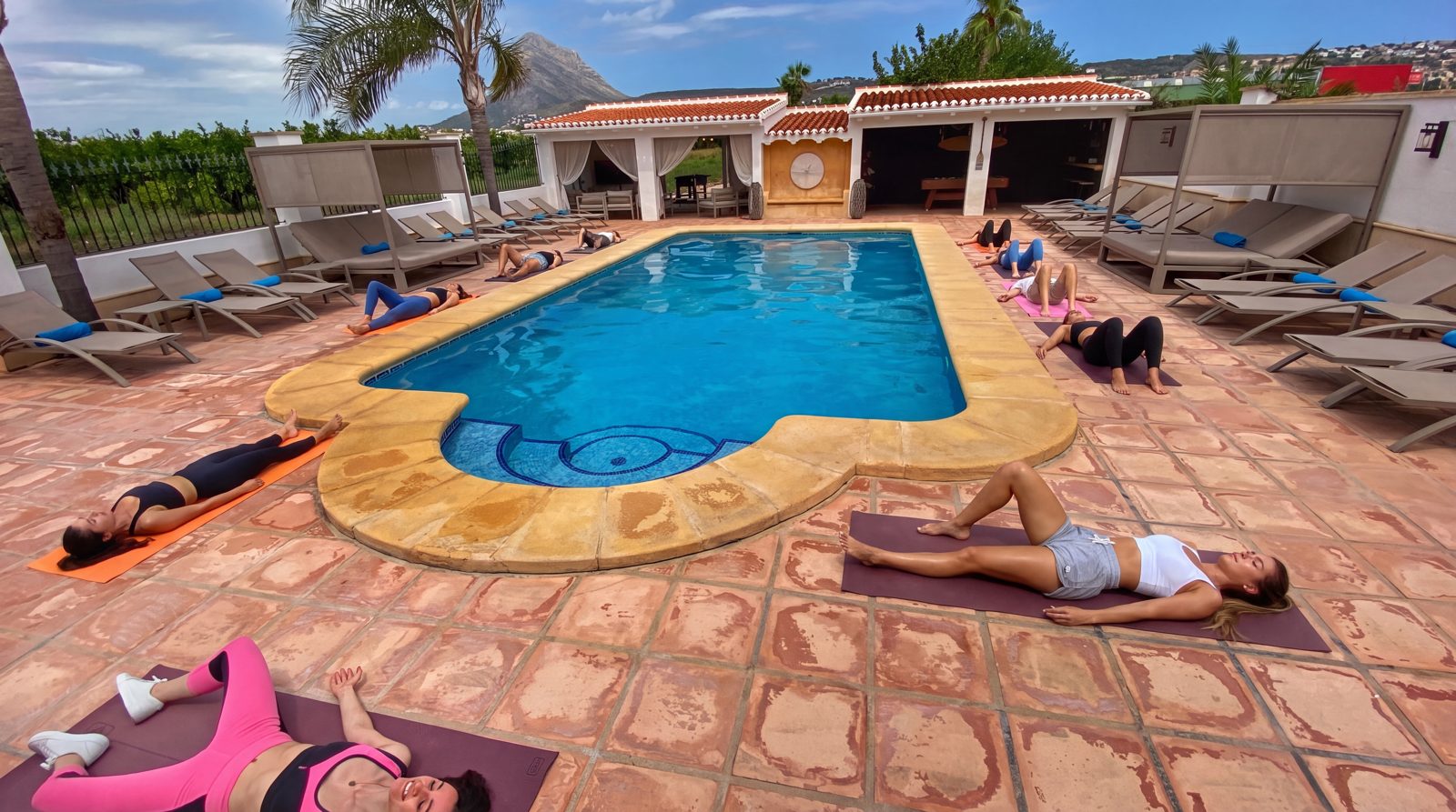 Yogasessie op matten naast het zoutwaterzwembad van Villa Palmview