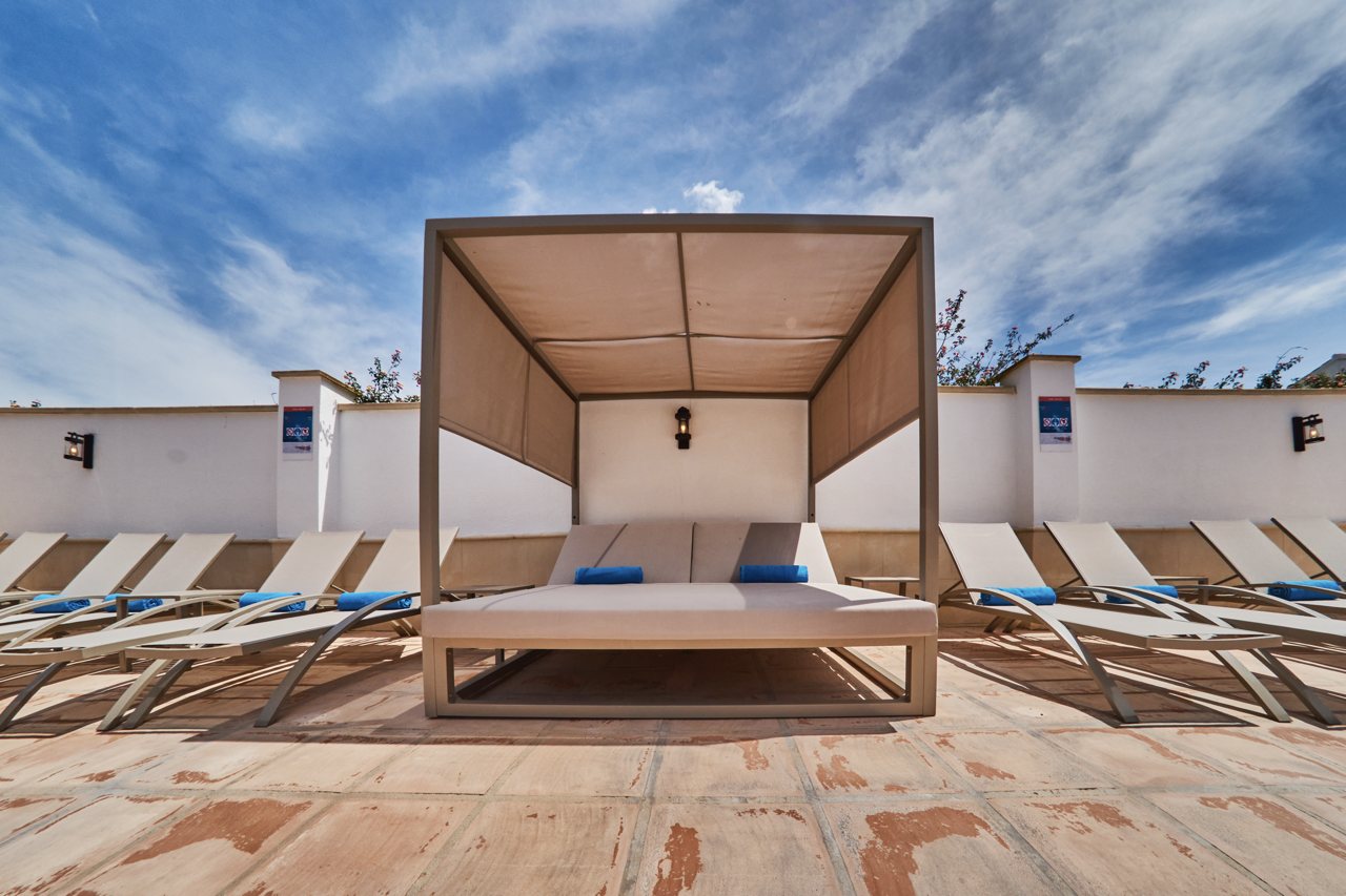 Canopied daybed by the pool under a dramatic sky